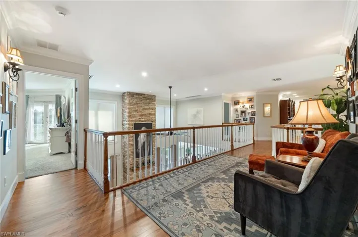 Living area with visible vents, baseboards, crown molding, recessed lighting, and wood finished floors