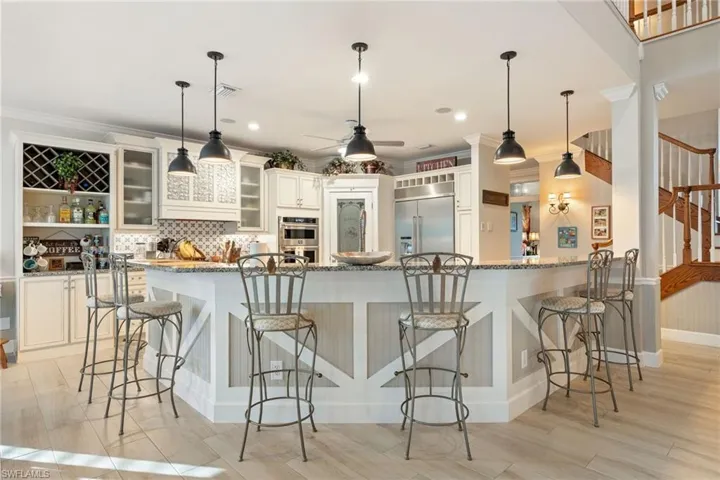 Kitchen featuring light stone countertops, ceiling fan, a breakfast bar, and appliances with stainless steel finishes