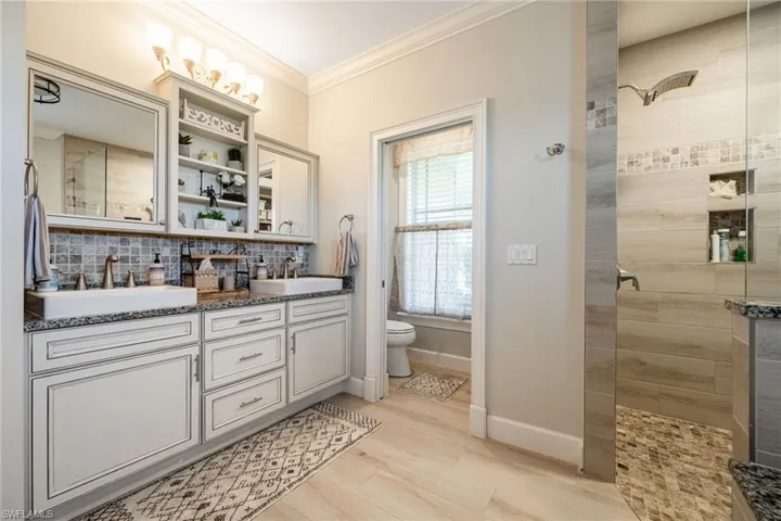 Bathroom with a walk in shower, a sink, and crown molding