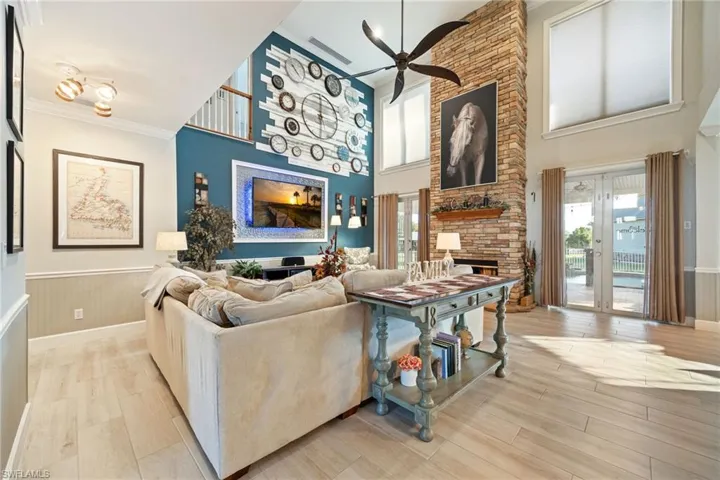 Living room featuring ceiling fan, wood finished floors, a wainscoted wall, and a fireplace