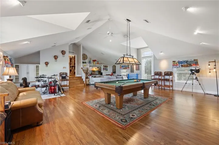 Rec room with pool table, a ceiling fan, vaulted ceiling, visible vents, and wood finished floors