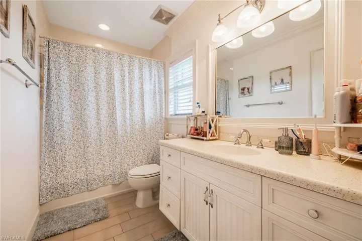 Bathroom with toilet, vanity, ornamental molding, and visible vents