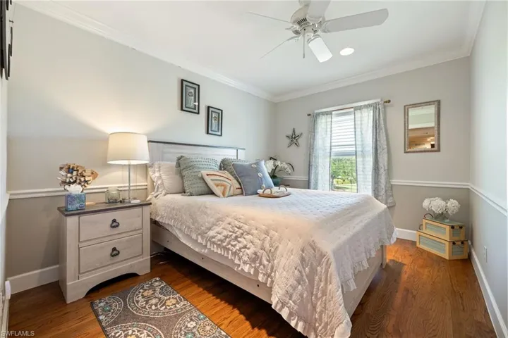 Bedroom featuring dark wood-style flooring, baseboards, ornamental molding, and ceiling fan