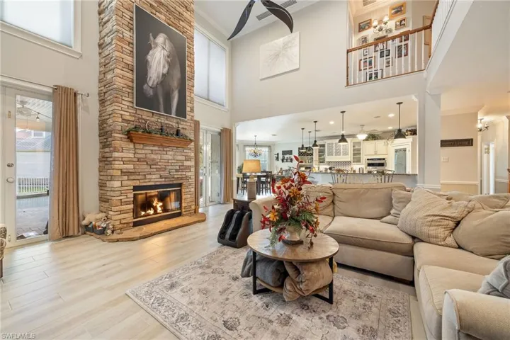 Living area featuring a notable chandelier, light wood-style floors, a fireplace, crown molding, and a towering ceiling