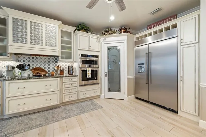 Kitchen featuring dark stone counters, wood finish floors, visible vents, appliances with stainless steel finishes, and backsplash