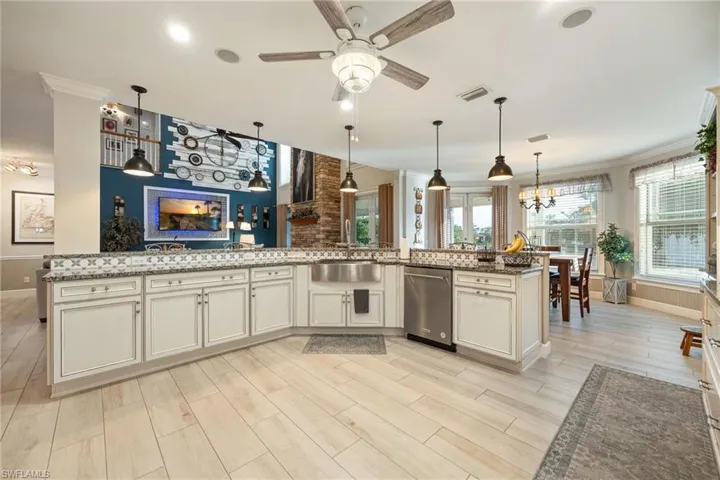 Kitchen with ceiling fan with notable chandelier, stone counters, a sink, and wood tiled floor