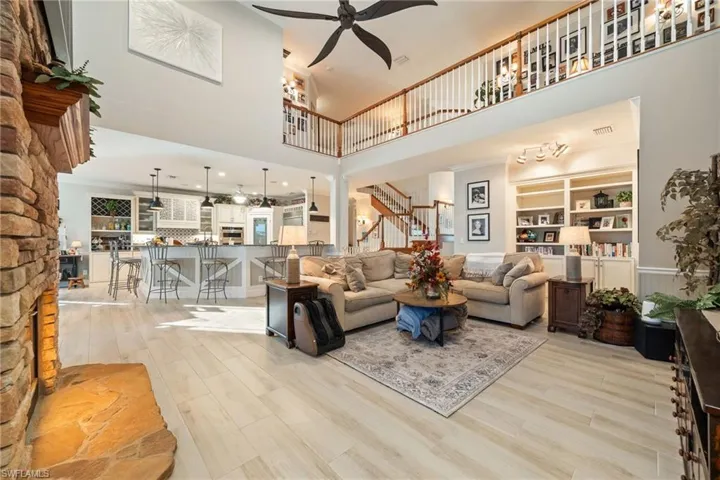 Living room featuring light wood-type flooring, ceiling fan, visible vents, and stairs