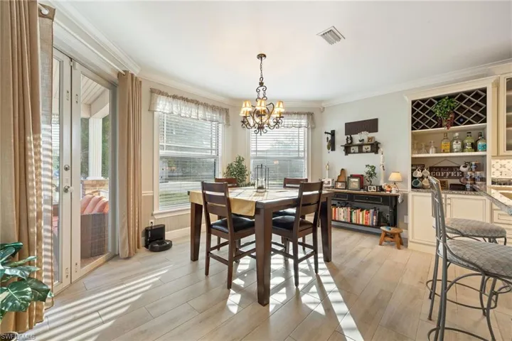 Dining space with light wood-style flooring, visible vents, an inviting chandelier, and crown molding