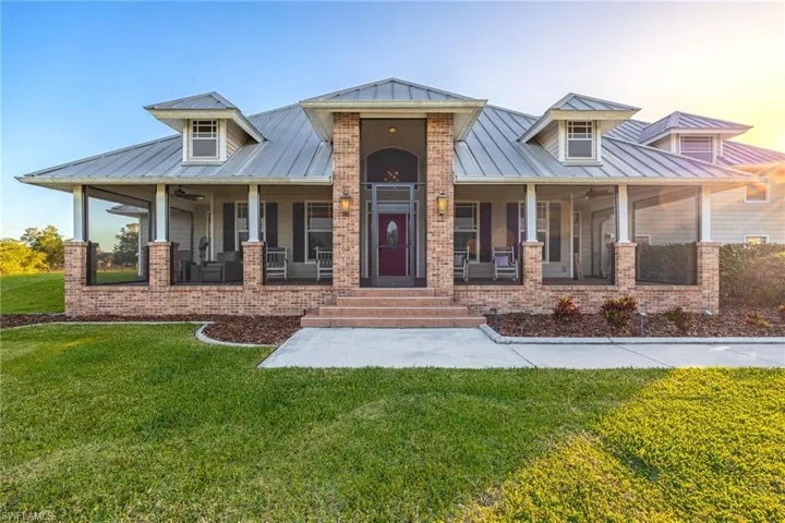 View of front of house featuring a front yard, brick siding, a standing seam roof, metal roof, and covered porch