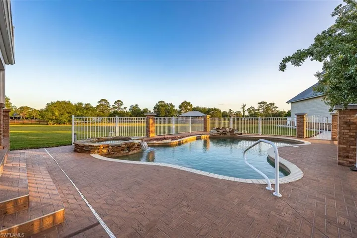 View of swimming pool featuring a patio area, fence, a yard, and a pool with connected hot tub