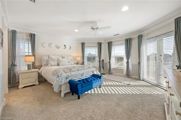 Bedroom featuring light carpet, multiple windows, access to exterior, and ornamental molding