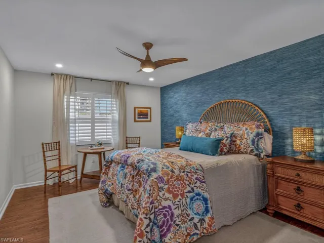 Furnished second Bedroom with fun grass cloth accent wall. Wood floors, skimmed and painted ceiling and walls with recessed lighting.