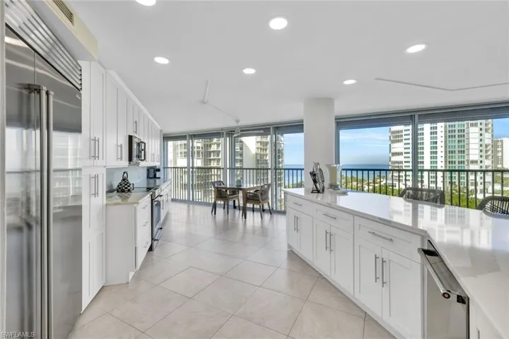 Kitchen featuring high quality appliances, expansive windows, light tile patterned floors, and white cabinets