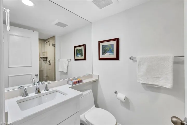 Bathroom with vanity, an enclosed shower, and toilet