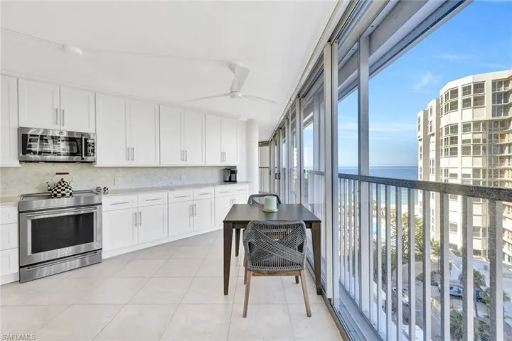Kitchen with ceiling fan, appliances with stainless steel finishes, a water view, white cabinets, and decorative backsplash