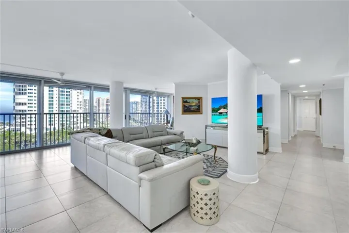 Tiled living room featuring ceiling fan and a wall of windows