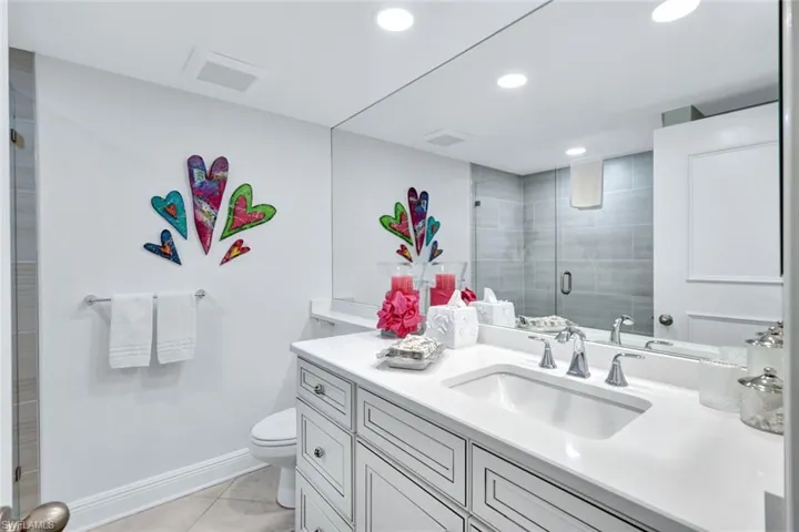 Bathroom with vanity, toilet, a shower with shower door, and tile patterned flooring