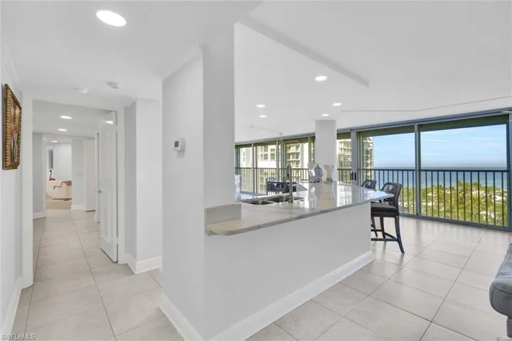Kitchen featuring sink, light tile patterned floors, a wall of windows, a water view, and kitchen peninsula