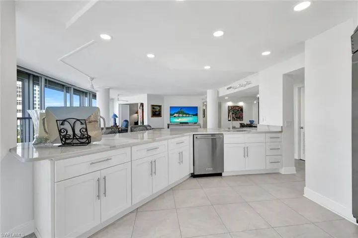 Kitchen with sink, dishwasher, ceiling fan, white cabinetry, and kitchen peninsula