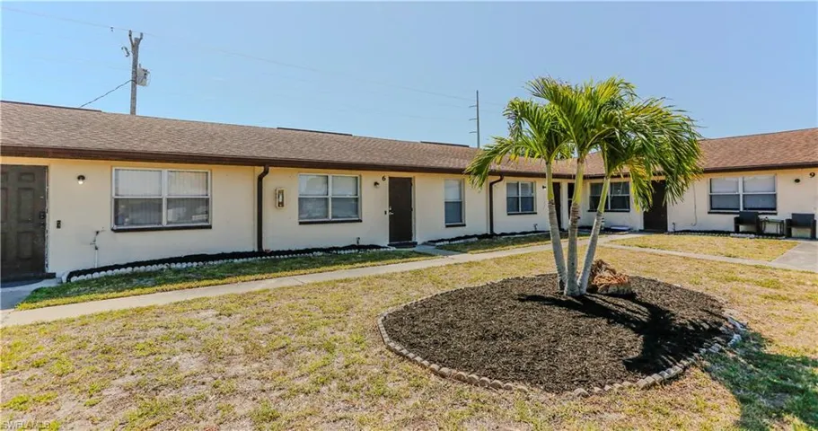 Two single-story buildings with light-colored stucco exteriors and brown shingle roofs
