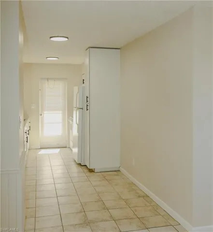 Tiled flooring extending through a galley-style kitchen with white cabinetry and appliances