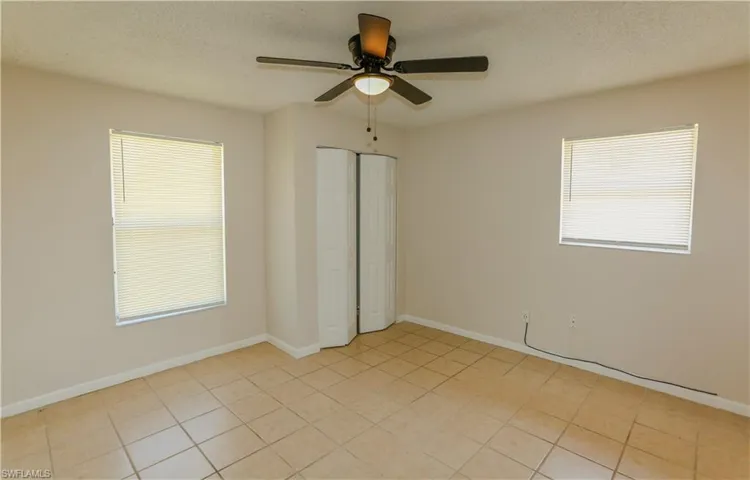 Room featuring neutral-toned walls, square tile flooring, and a ceiling fan with light fixture