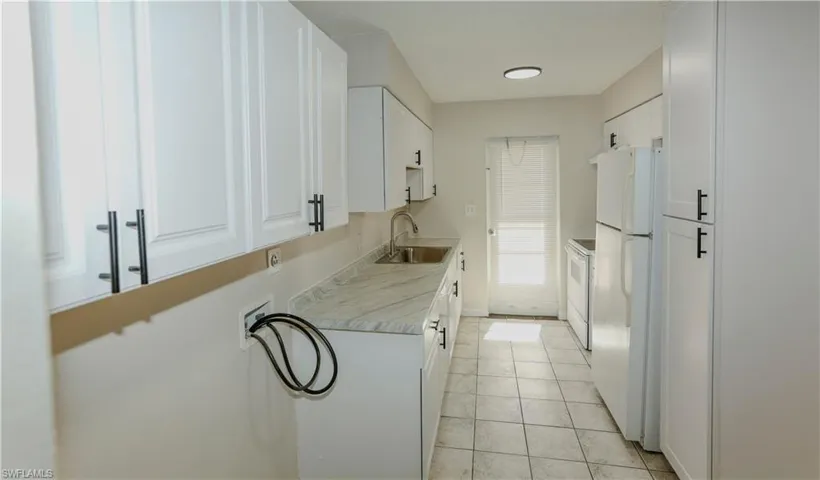 Kitchen featuring white cabinetry with black hardware, light-toned countertops, and tiled flooring