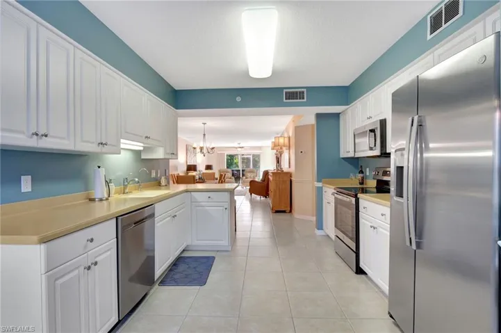 Kitchen featuring appliances with stainless steel finishes, visible vents, a sink, and a notable chandelier