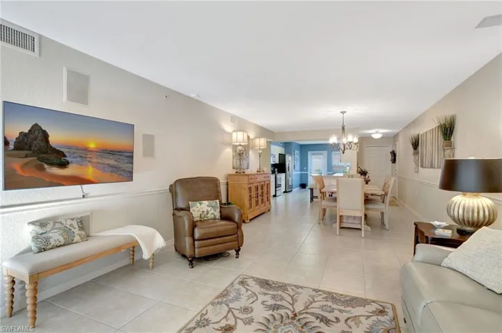 Living area featuring light tile patterned floors, baseboards, visible vents, and a chandelier