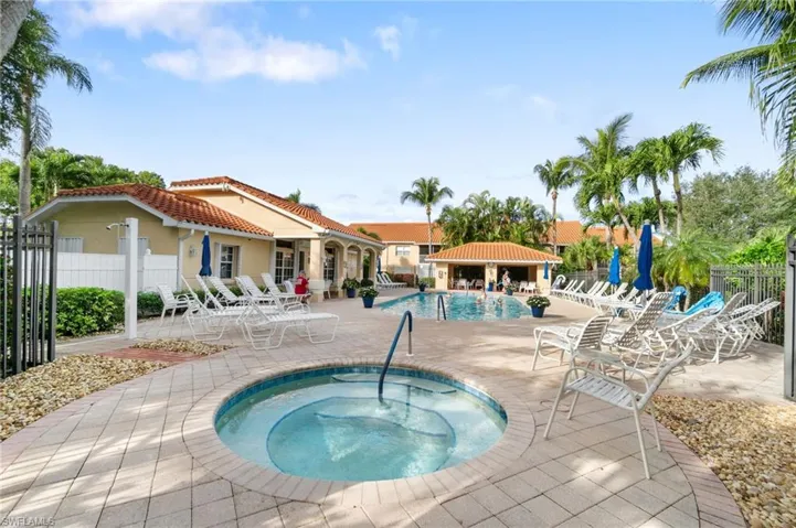 Pool with a patio, a community hot tub, and fence