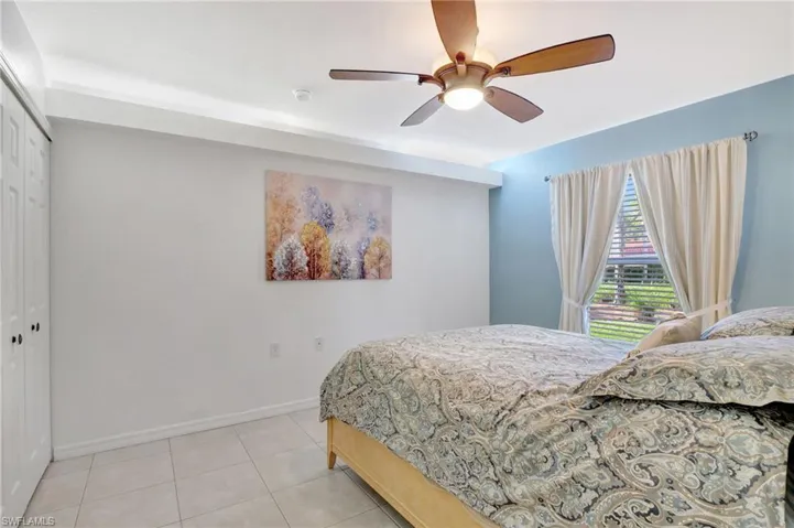 Bedroom featuring light tile patterned floors, ceiling fan, baseboards, and a closet