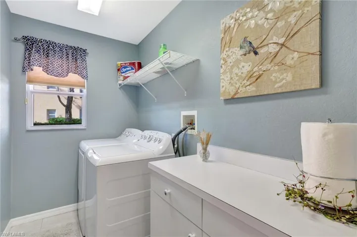 Washroom featuring washer and dryer, tile patterned flooring, cabinet space, and baseboards