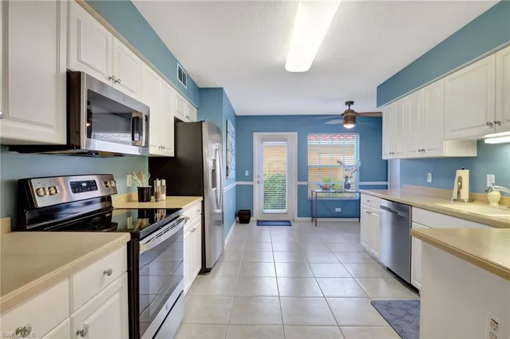 Kitchen featuring light countertops, visible vents, appliances with stainless steel finishes, light tile patterned flooring, and a sink