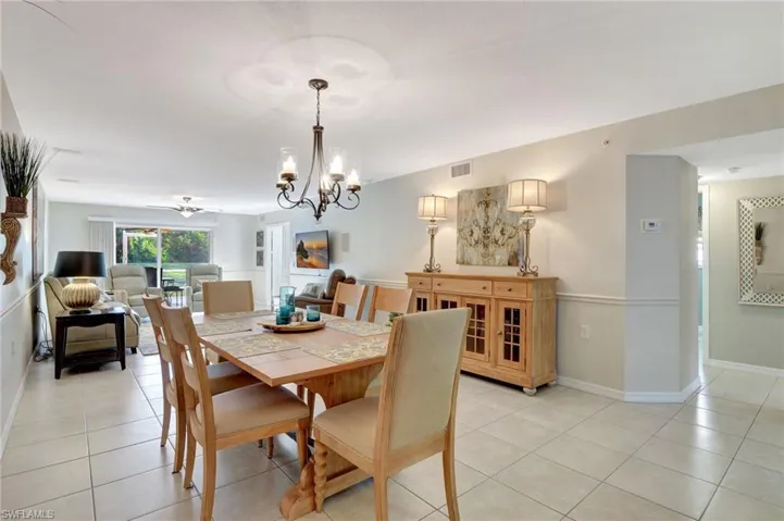 Dining area featuring light tile patterned floors, baseboards, visible vents, and an inviting chandelier