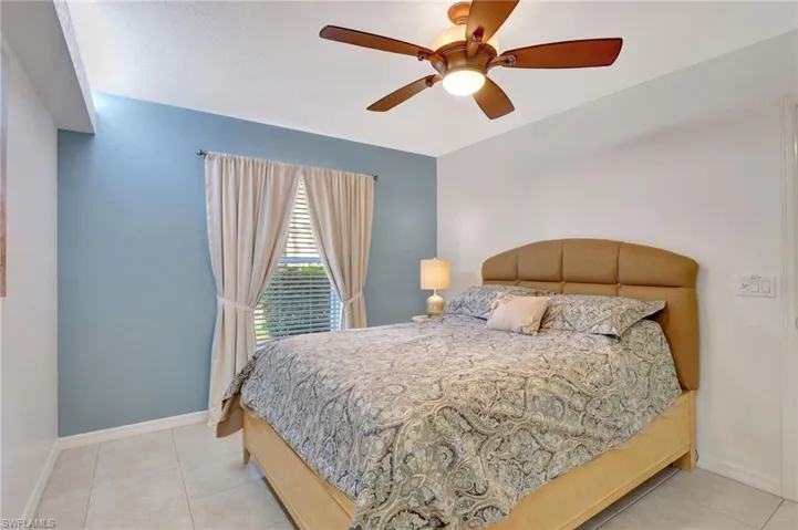Bedroom with ceiling fan, baseboards, and tile patterned floors