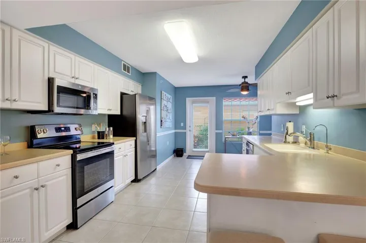 Kitchen with light tile patterned flooring, a sink, visible vents, a ceiling fan, and appliances with stainless steel finishes