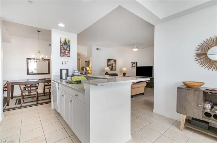 Kitchen with light tile patterned floors, open floor plan, dishwasher, arched walkways, and a sink