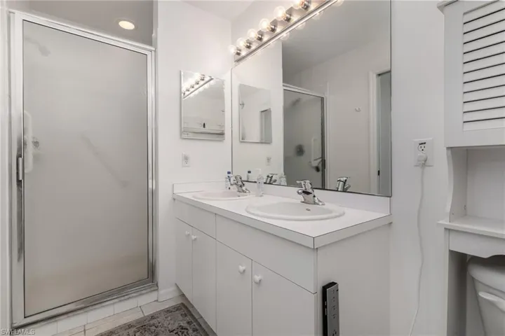 Bathroom featuring a stall shower, toilet, and double vanity