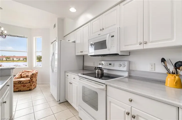Kitchen featuring white appliances, white cabinetry, light countertops, light tile patterned flooring, and recessed lighting