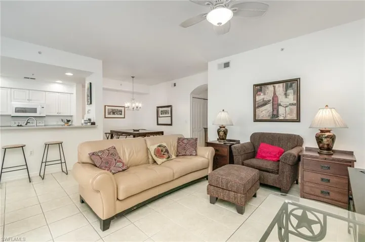 Living room featuring arched walkways, light tile patterned floors, a chandelier, a ceiling fan, and recessed lighting