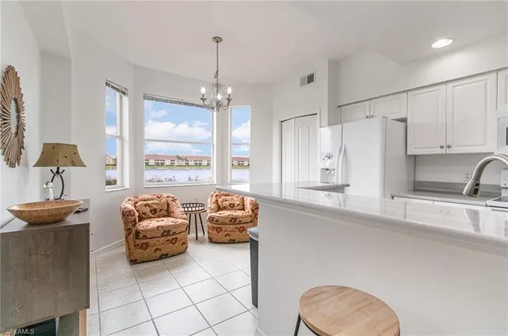 Kitchen with white appliances, light tile patterned flooring, white cabinets, a water view, and light countertops