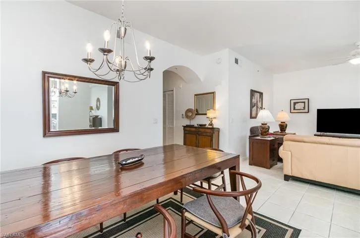 Dining space with a chandelier, light tile patterned floors, and arched walkways