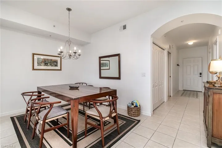 Dining area with arched walkways, light tile patterned floors, a chandelier, and baseboards