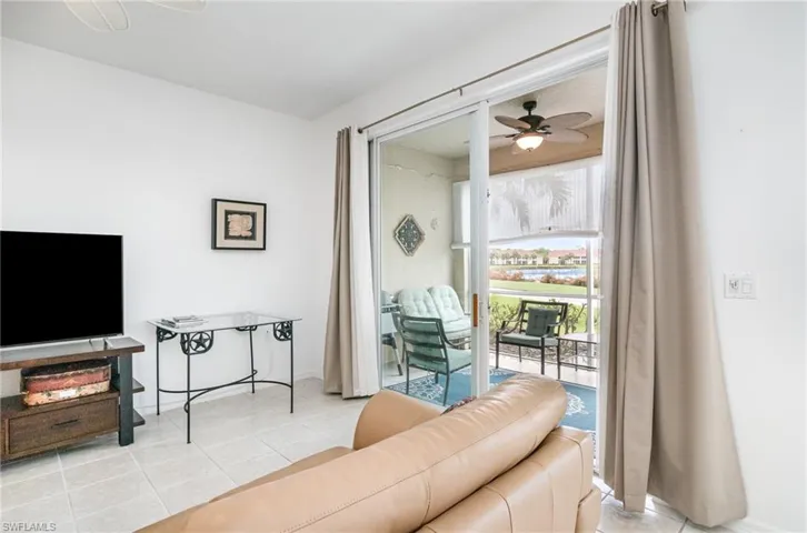 Living area with a ceiling fan, light tile patterned floors, and baseboards