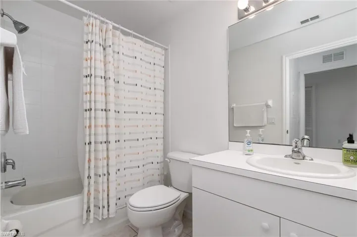 Full bathroom featuring toilet, shower / bathtub combination with curtain, vanity, and tile patterned flooring