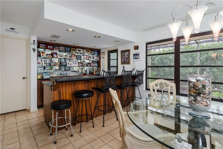 Indoor dry bar with dark countertops, recessed lighting, light tile patterned floors, and open shelves