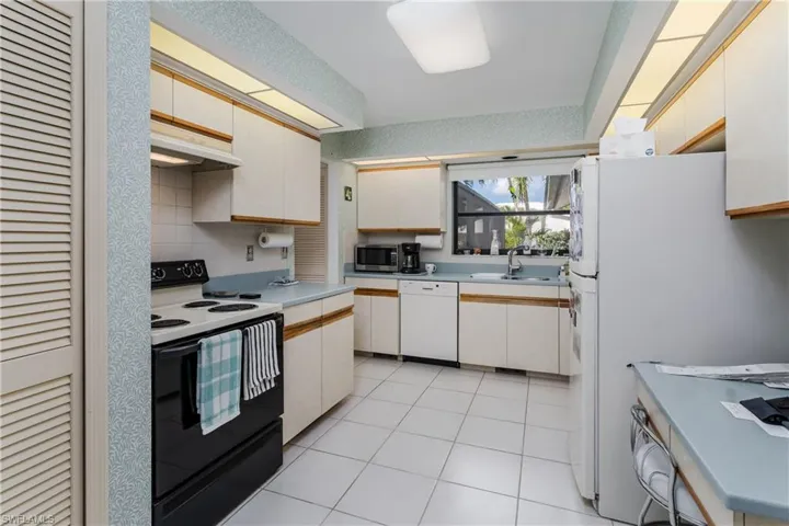 Dual tone kitchen with white appliances, light countertops, two tone color scheme, and light tile patterned flooring