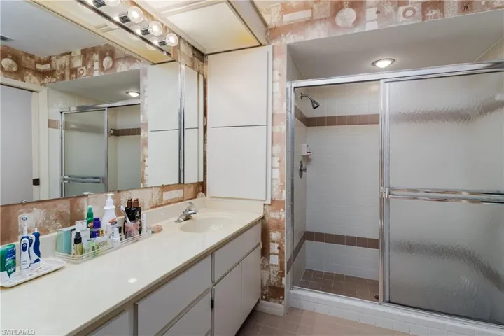 Bathroom featuring vanity, a shower stall, tile walls, and backsplash