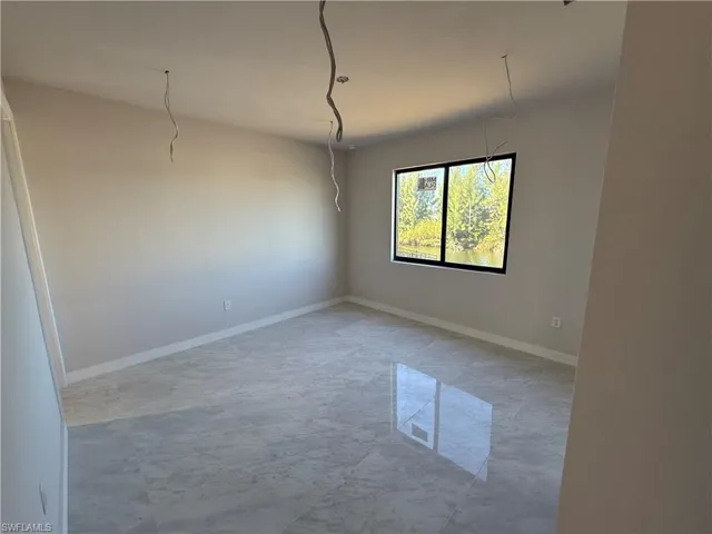 Empty room featuring light marble finish flooring and baseboards