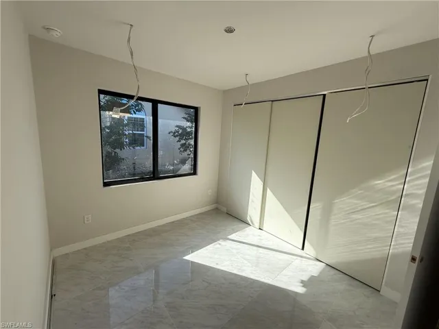 Unfurnished bedroom with light marble finish floors and baseboards